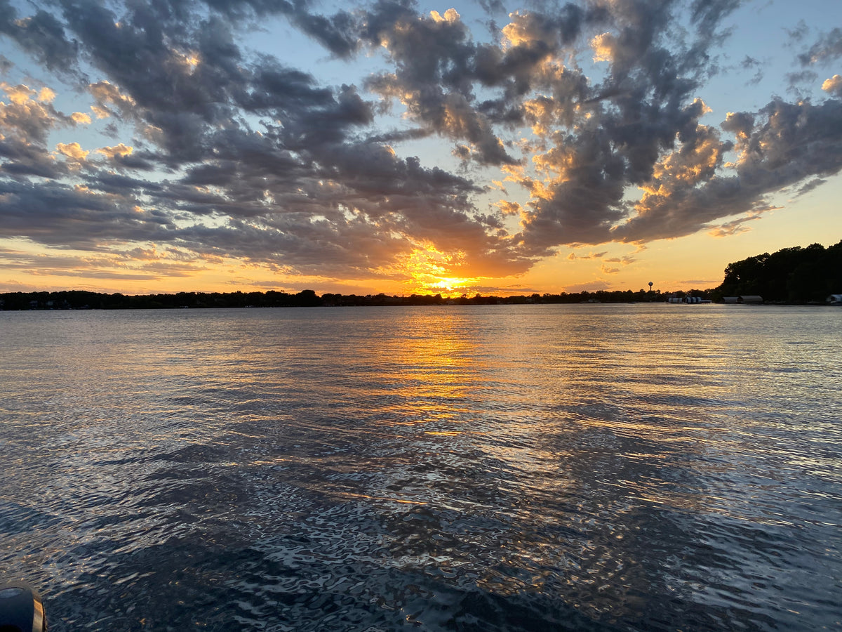 Sunset over a body of water with clouds reflecting on the surface